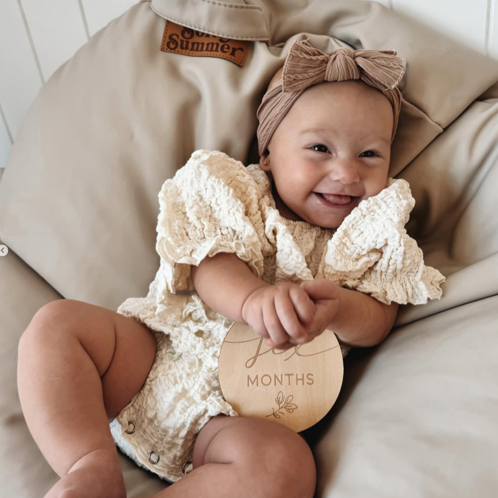 6 month old wearing elegant white crinkle romper
