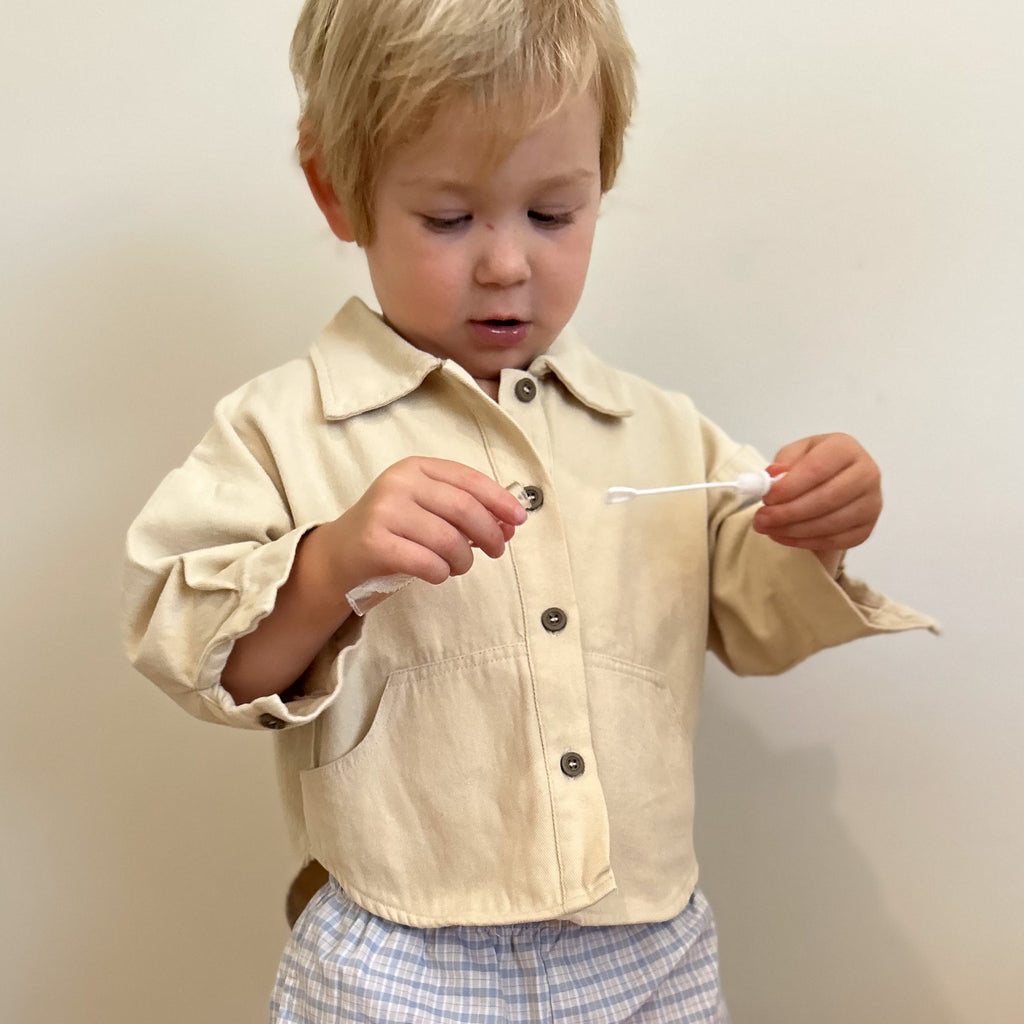 Baby wearing cream button-up shirt with drop-tail hem and front pockets