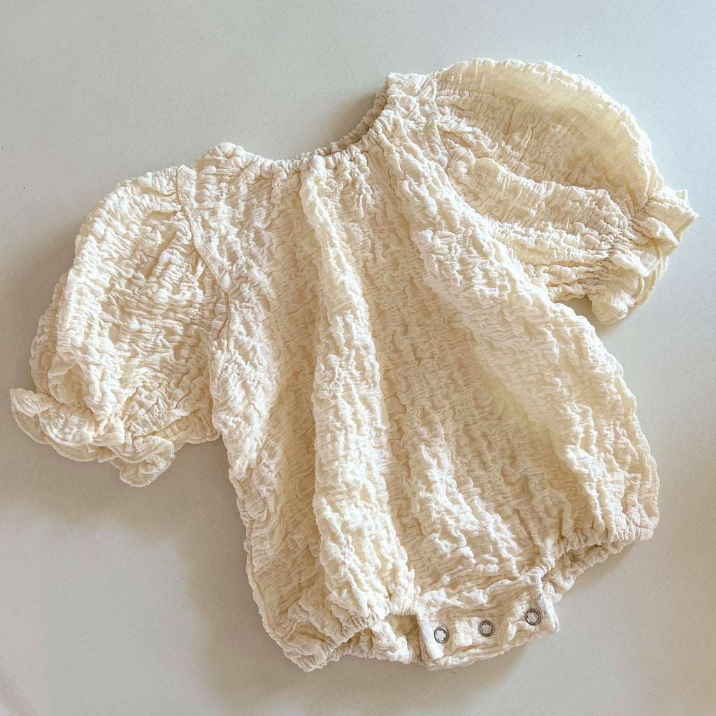 Neutral baby romper with elasticated puff sleeves and textured crinkle cotton
