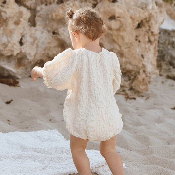 Baby wearing cream puff sleeve romper in lightweight crinkle cotton fabric